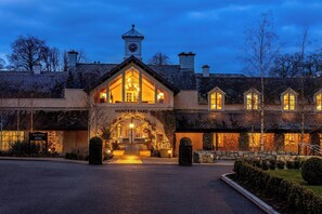 A building with a stone facade, a clock tower, and a warm-lit entrance. - Mount Juliet Estate, Autograph Collection (Thomastown)