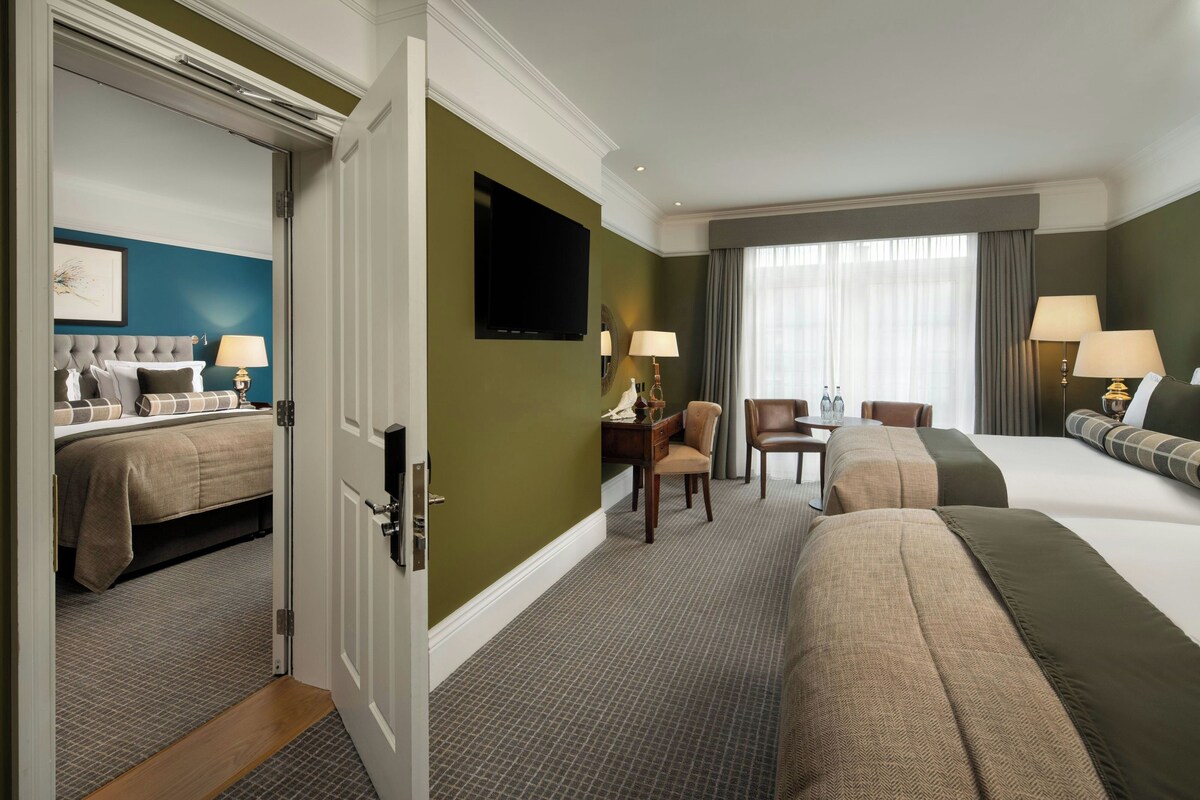 A hotel room with a bed, a desk, a chair, a television, and a window with curtains.