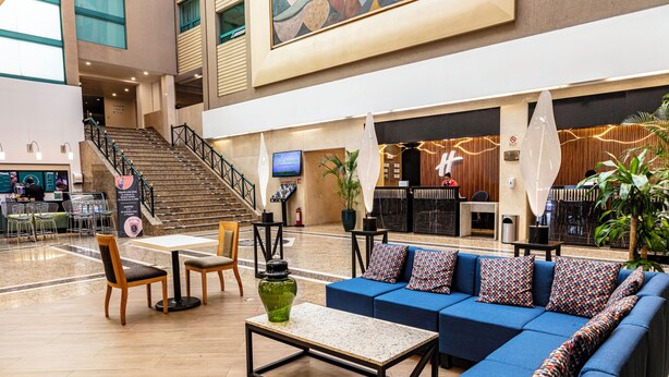 A spacious lobby with a blue sofa, wooden chairs, a coffee table, a staircase, and a reception desk. - Holiday Inn Ciudad De Mexico-Trade Center by IHG (Mexico City)
