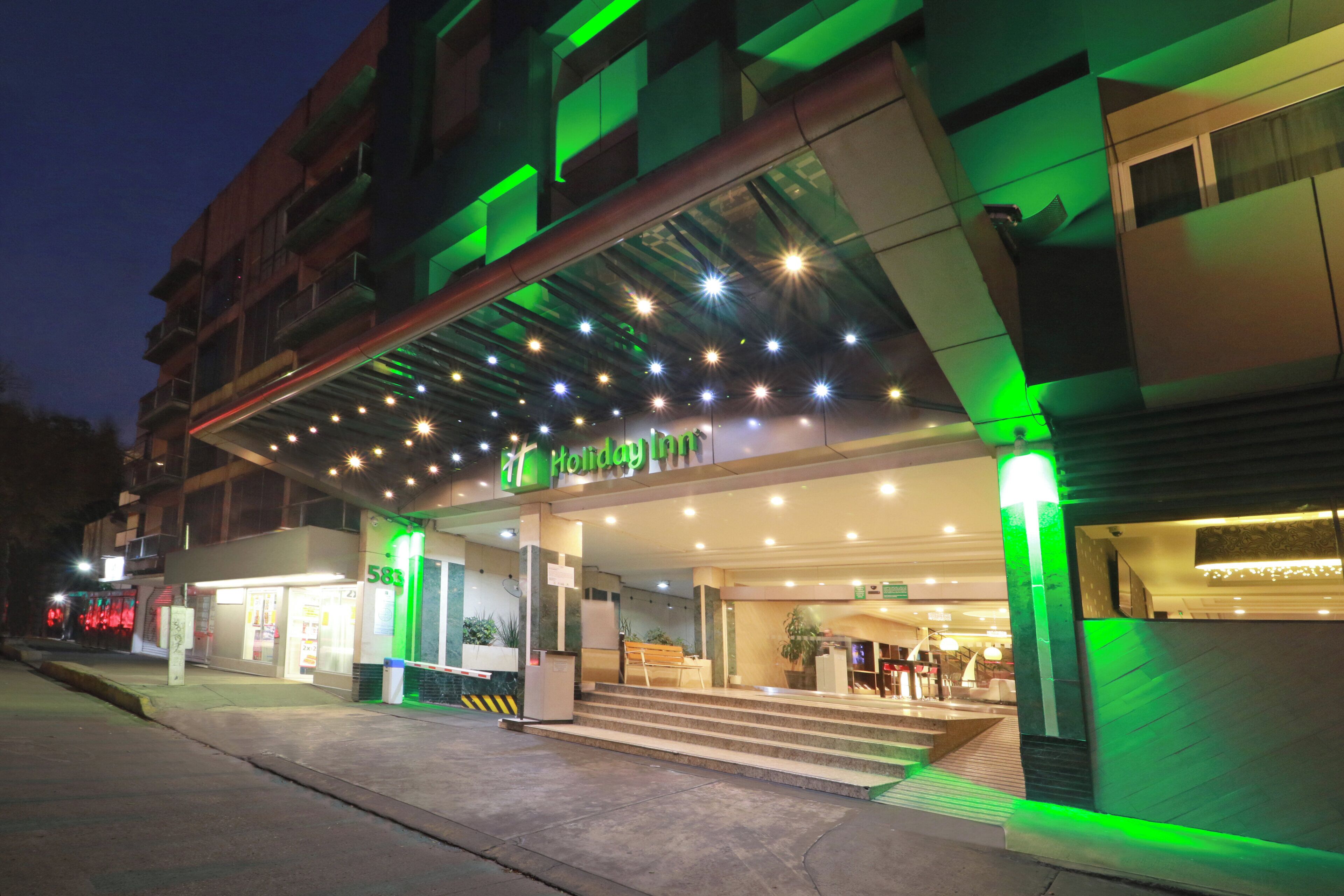 Ein Hotel mit Eingangsbereich, einem überdachten Gang, Stufen zum Eingang und einem Schild mit dem Namen 'Holiday Inn'.