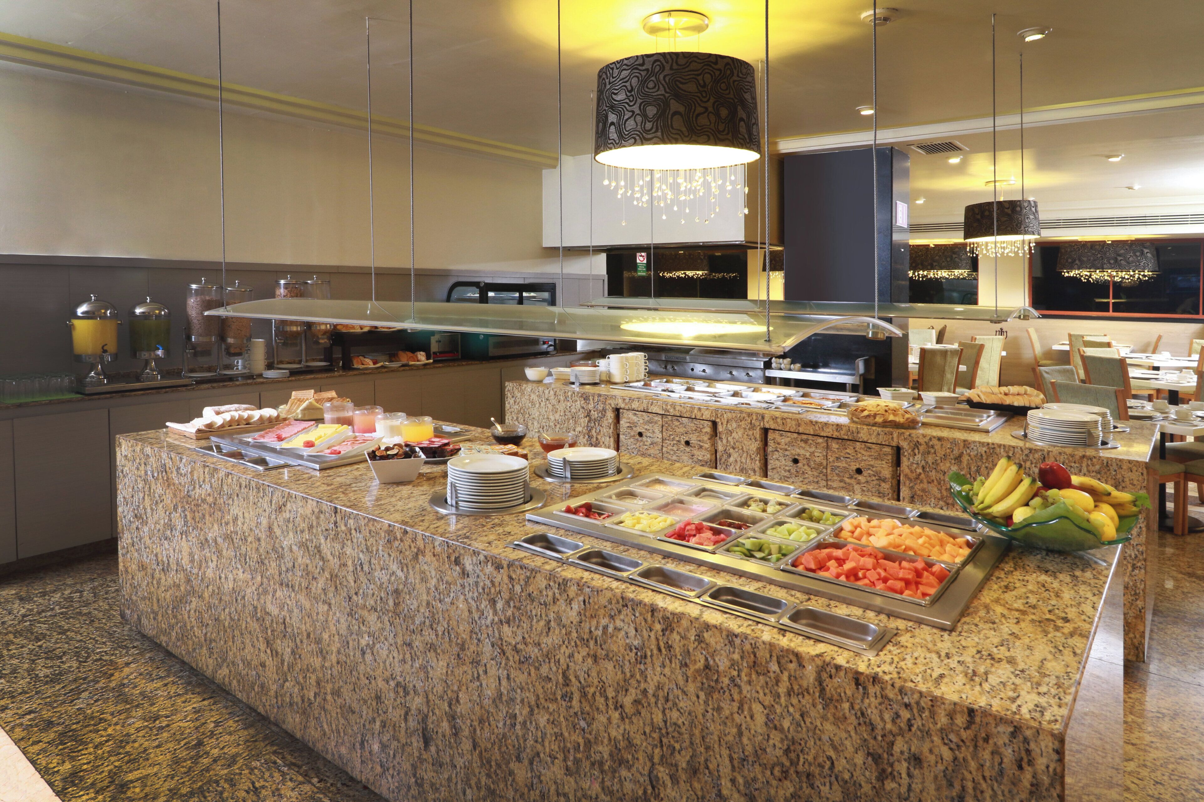A buffet area with a variety of food options, including fruits, vegetables, and prepared dishes, set in a modern kitchen environment.