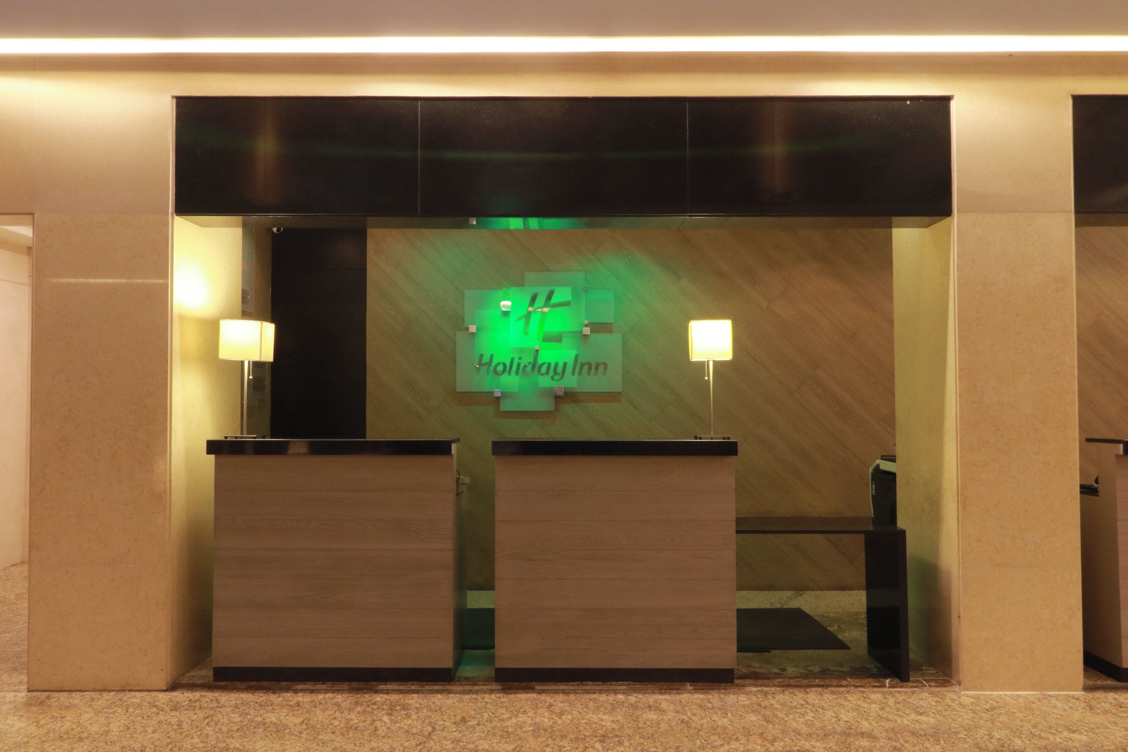 Una mesa de recepción con un letrero de 'Holiday Inn' y dos lámparas fijadas a la pared.
