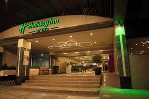 A Holiday Inn entrance with steps leading up to the door, a sign above the entrance, and a potted plant on the left. - Holiday Inn Ciudad De Mexico-Trade Center by IHG (Mexico City)