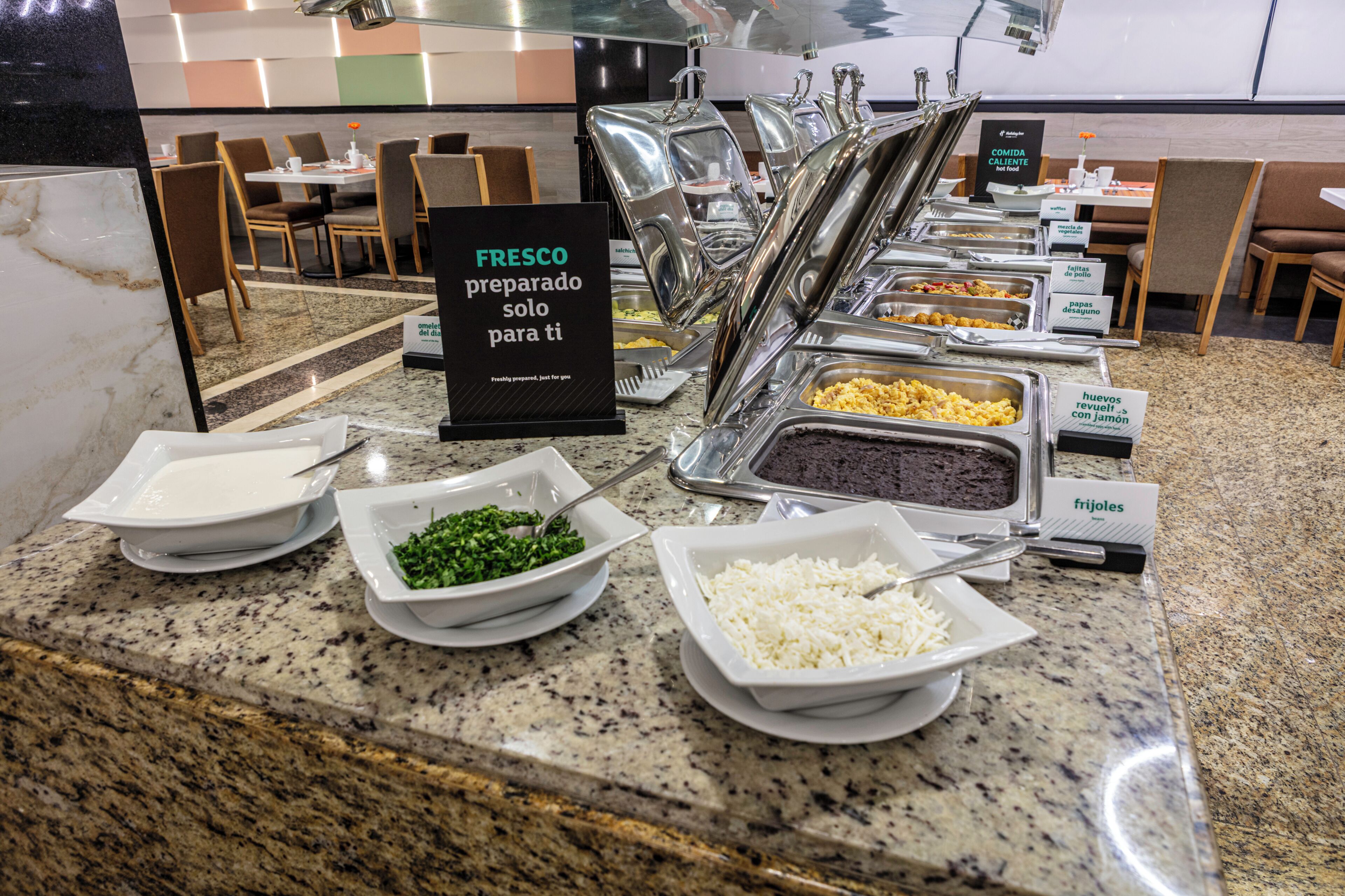 A buffet with labeled food stations including greens, rice, and beans.