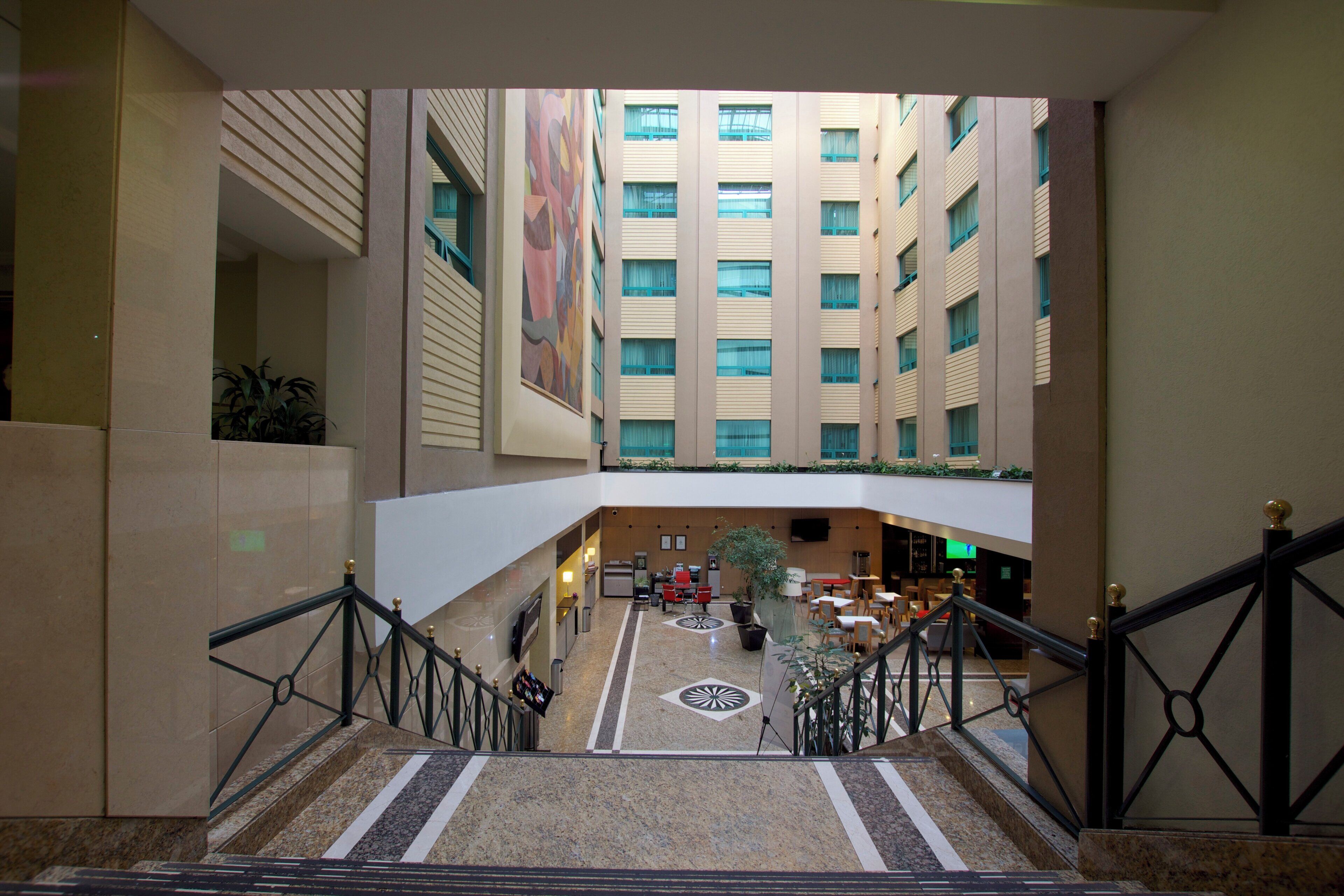 A hotel lobby with a central atrium, multiple floors, and a staircase.
