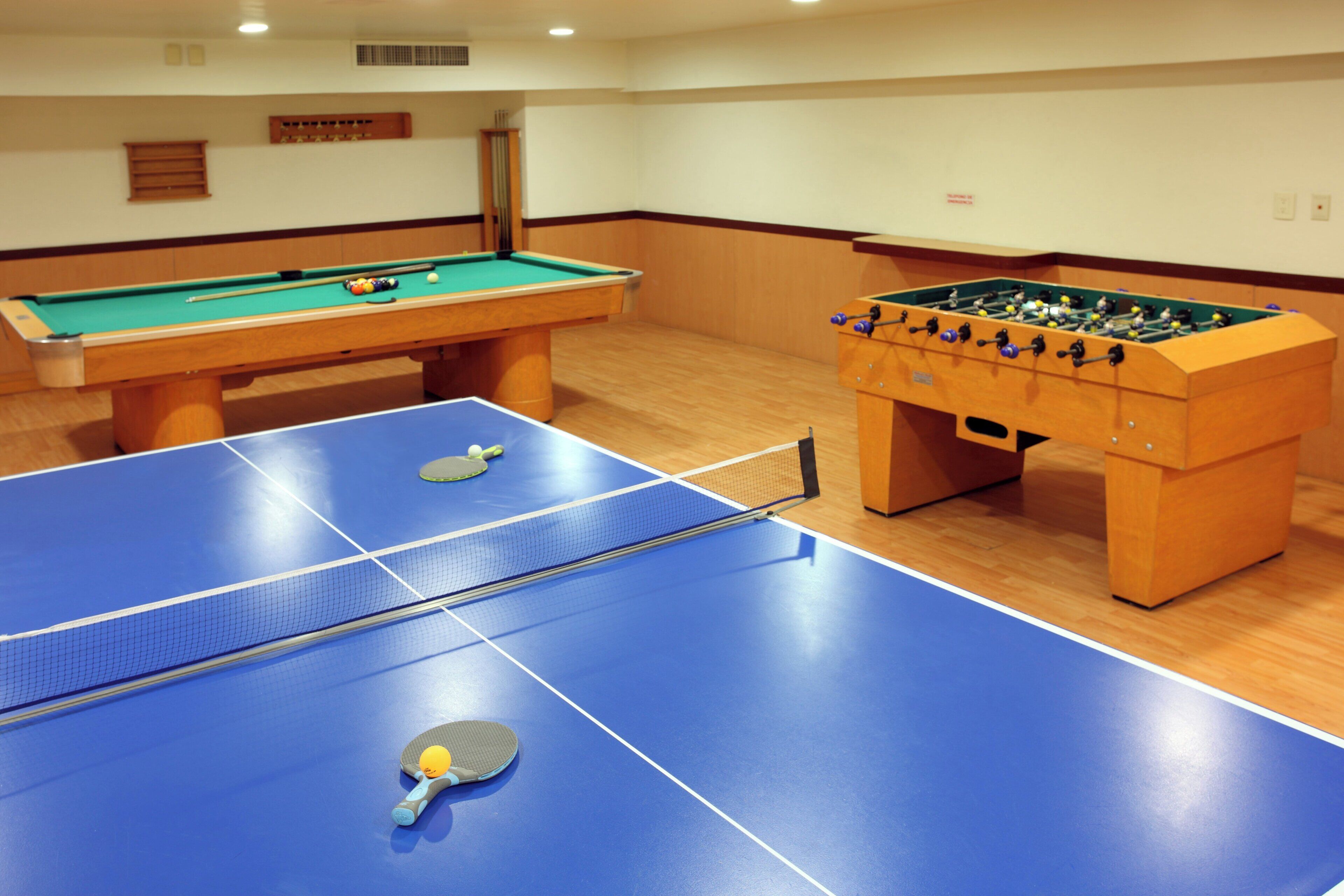 Una habitación con mesa de billar, mesa de fútbol de mesa y mesa de tenis.