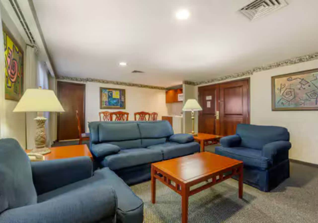 A living room with a sofa, two armchairs, a coffee table, and two lamps.
