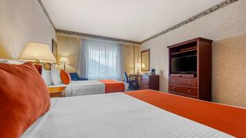 Une chambre d’hôtel avec deux lits, un bureau, une chaise, une télévision et une commode.