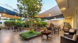 Un patio al aire libre con mobiliario, una chimenea y diversas plantas.