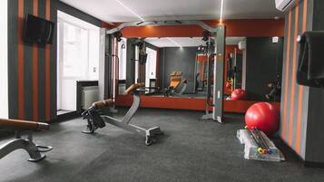 Un gimnasio con equipo de ejercicio, un espejo y una pelota roja para hacer ejercicio.