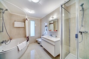 Un baño moderno con bañera, ducha envuelta en vidrio, inodoro y tocador con espejo.