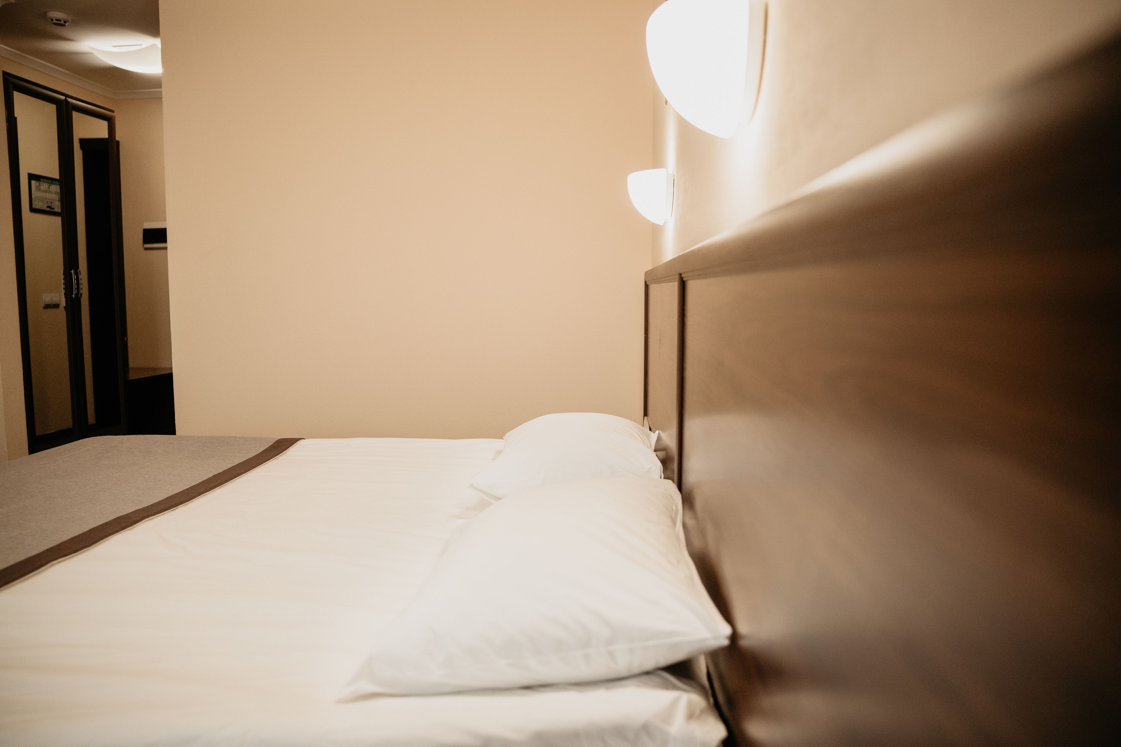 A hotel room with a bed, a wooden headboard, and a door.