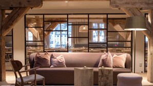 A modern living room with a wooden sofa, a wooden chair, a small table, and a lamp. - Hotel Brosundet (Ålesund)