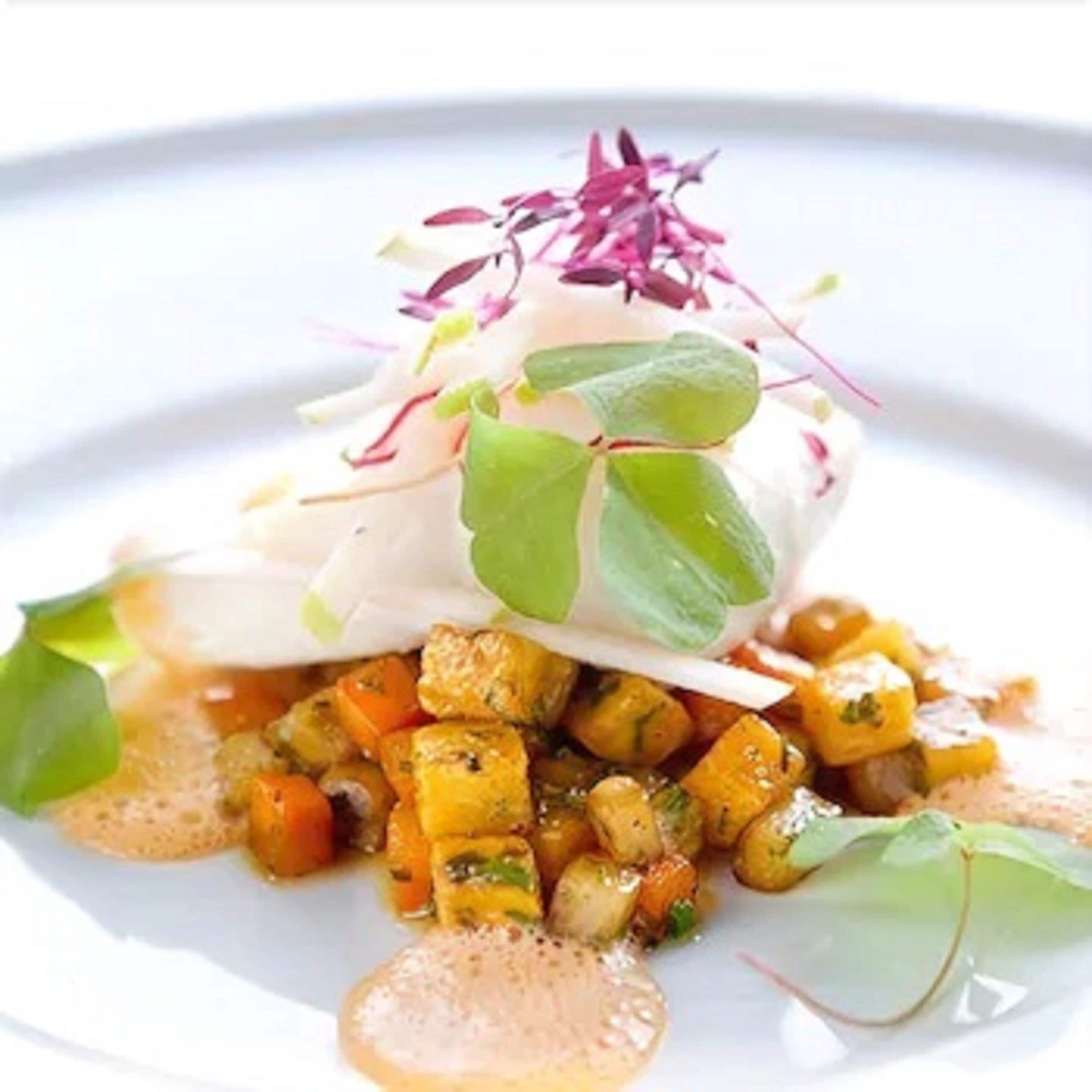 Un plato con un huevo escalfado, verduras y salsa.