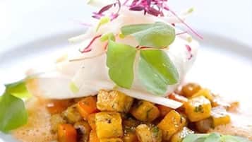 Un plato con un huevo escalfado, verduras y salsa.