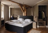 A modern bedroom with a large bed, wooden beams, a desk, and a walk-in closet.