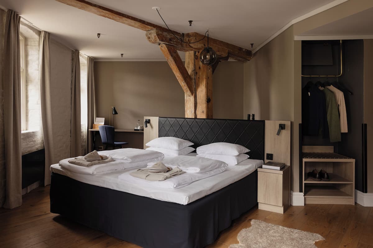 Ein modernes Schlafzimmer mit einem großen Bett, Holzbalken, einem Schreibtisch und einem begehbaren Kleiderschrank.