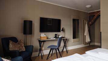 A hotel room with a bed, a desk with a chair, a TV, and a coat rack.