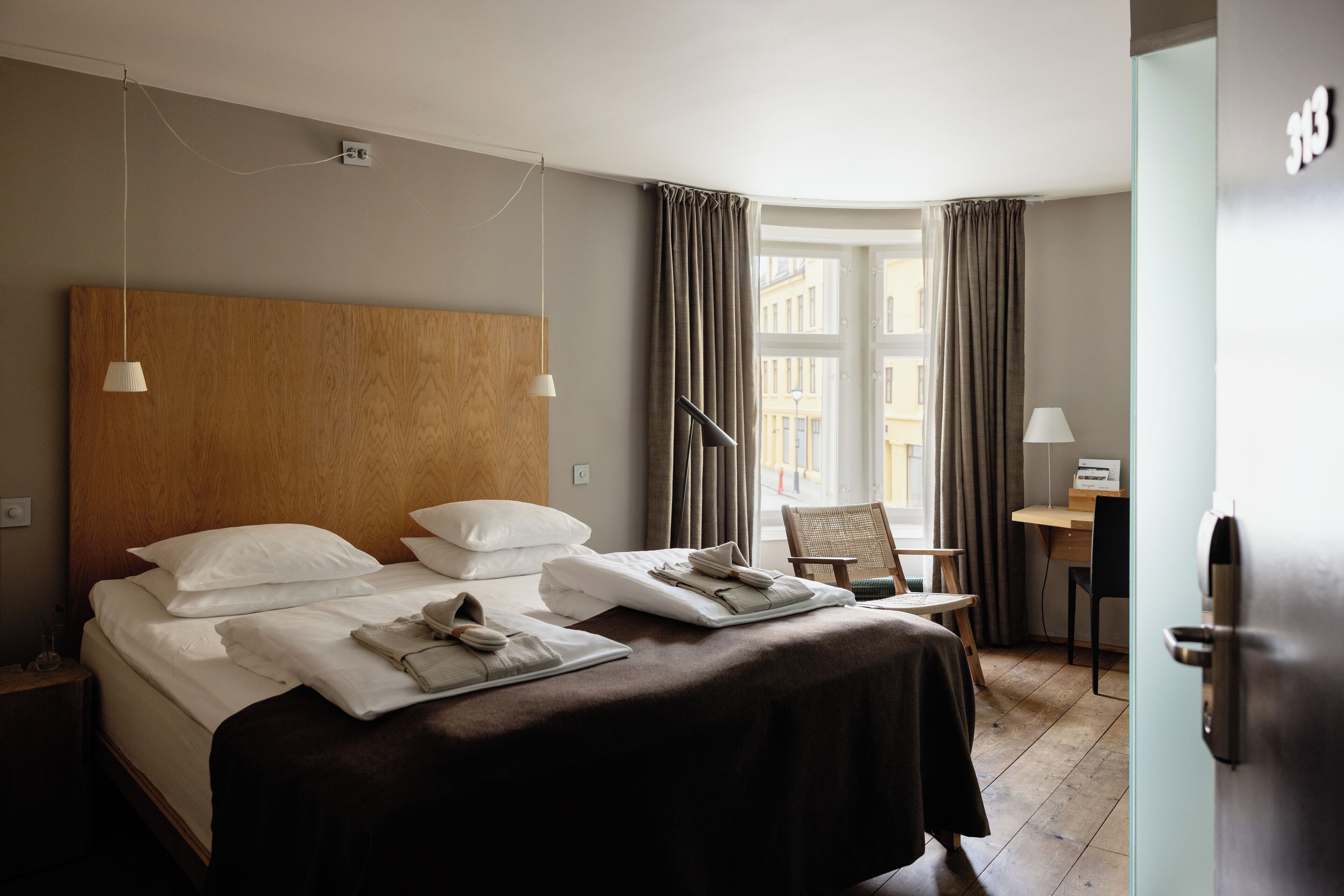 A hotel room with a large bed, two bedside tables, a desk, and a chair.