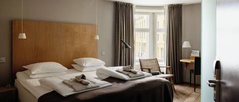 A hotel room with a large bed, two bedside tables, a desk, and a chair.