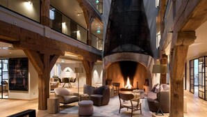 Un vestíbulo amplio con una chimenea grande, vigas de madera y cómodas zonas de estar.