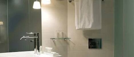 Une salle de bain moderne avec un grand miroir, un lavabo doté d’un porte-serviettes, des toilettes et un espace douche.