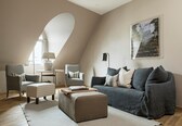 A modern living room with a grey sofa, two armchairs, a small table, and a lamp.