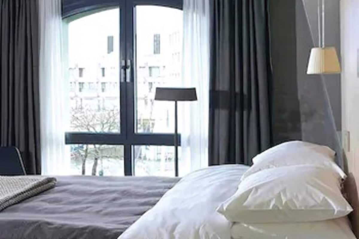 Ein Schlafzimmer mit Bett, Vorhängen, einem Fenster und einer Lampe.