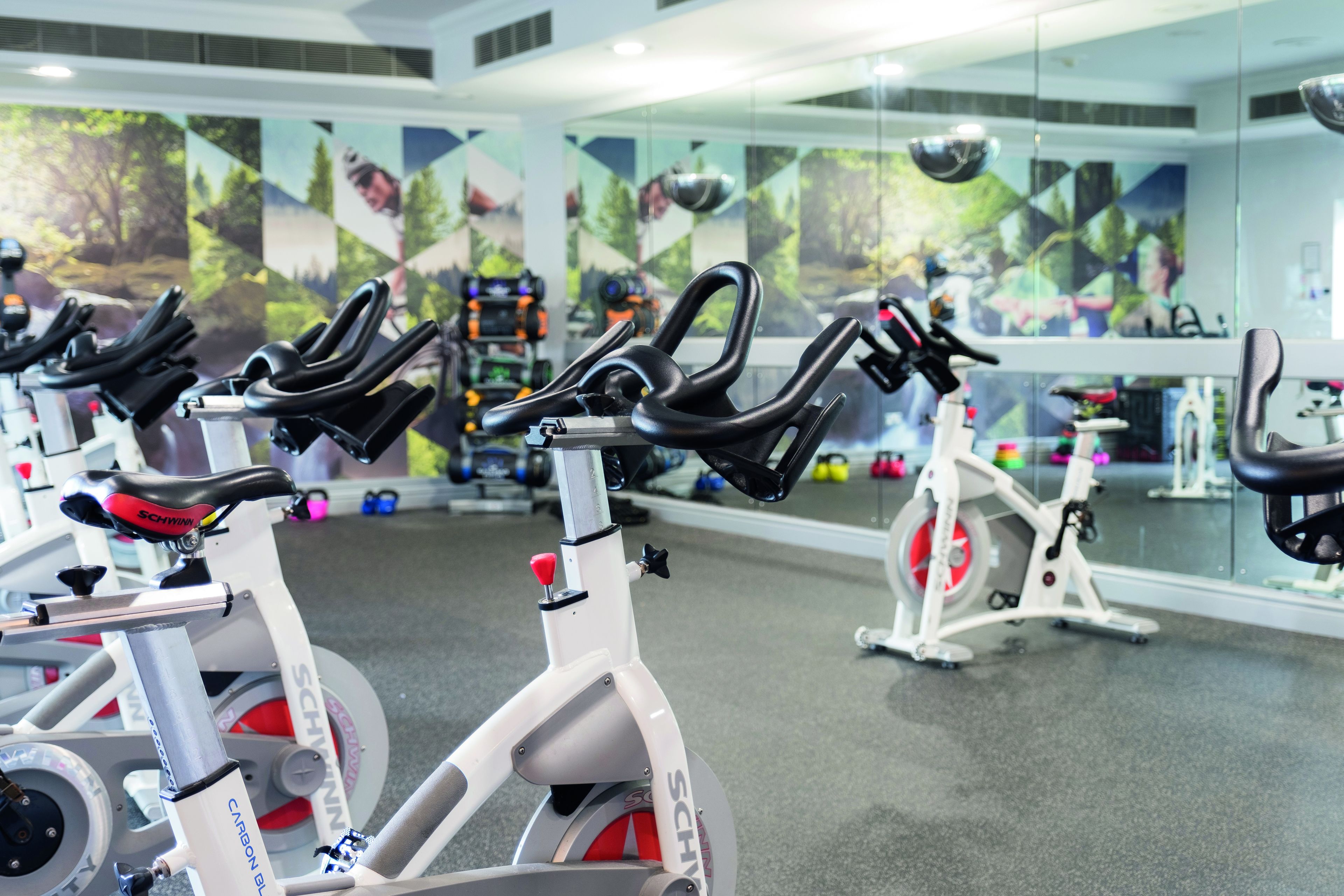 A gym with stationary bikes, a mirror wall, and exercise equipment.