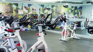 A gym with stationary bikes, a mirror wall, and exercise equipment.