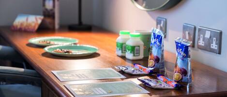 A wooden counter with green plates, juice bottles, and snack packets.