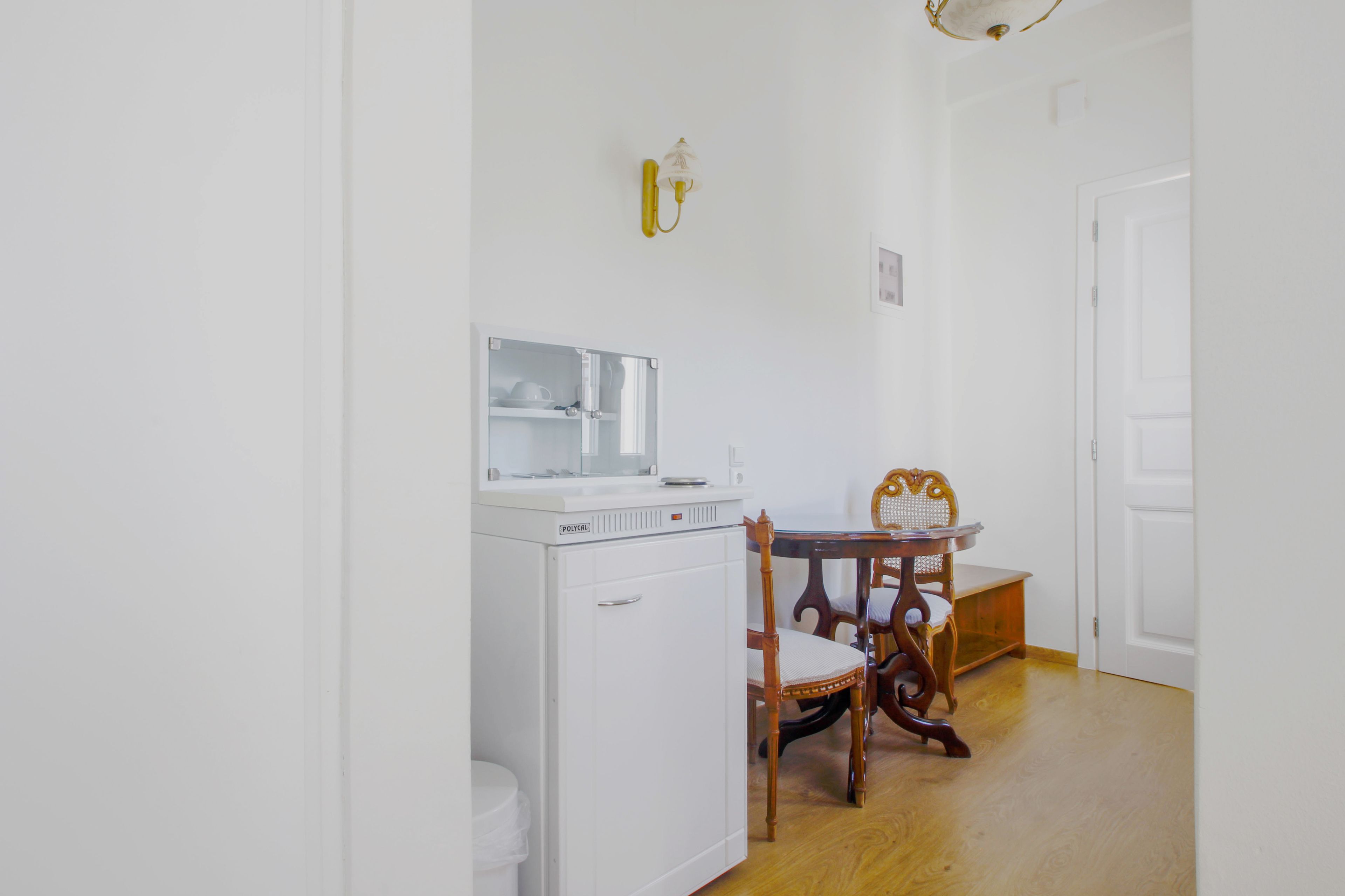 A compact kitchen with a refrigerator, a microwave, and a small dining table with chairs.