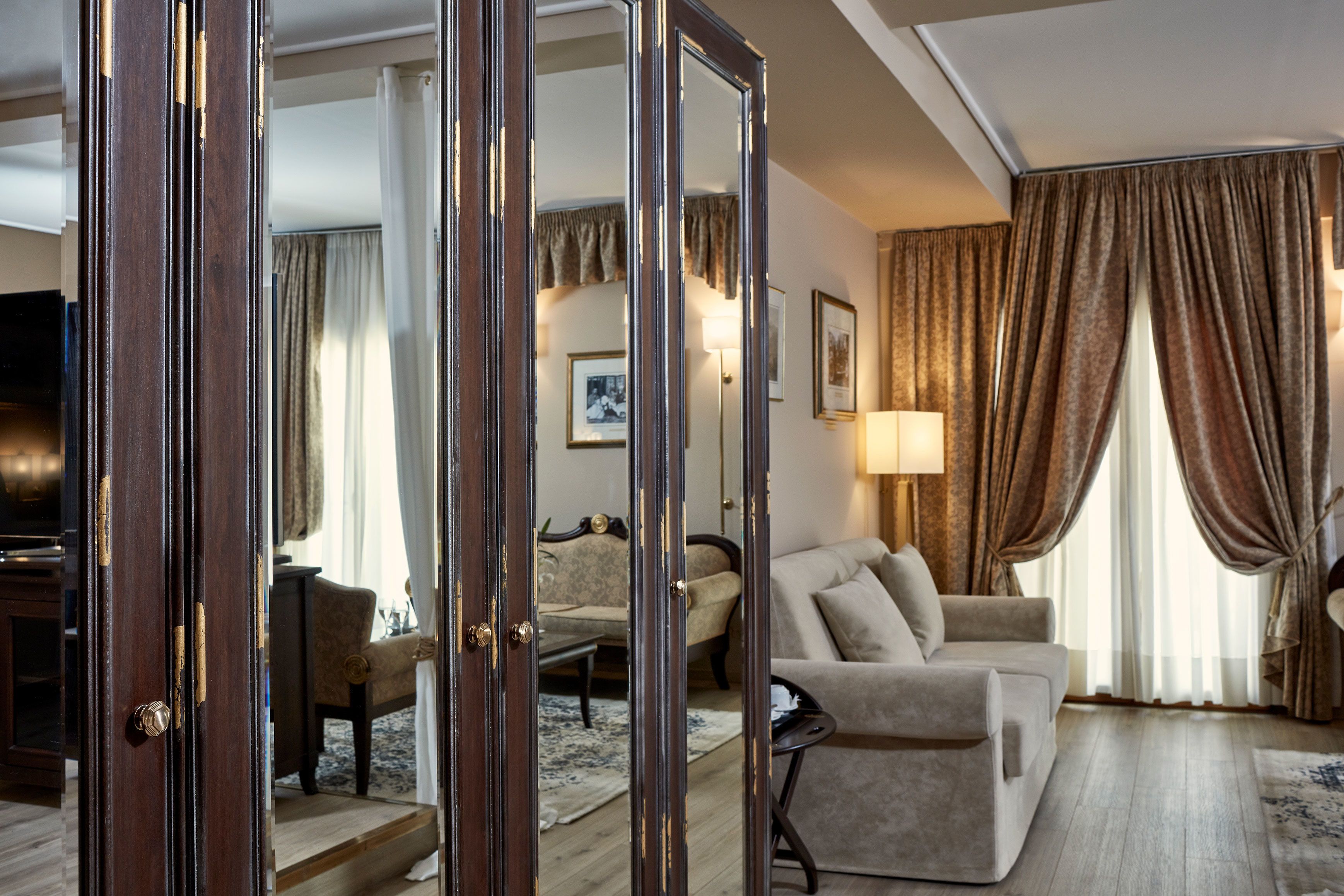 Un salón espacioso con un espejo grande, un sofá, una silla y un televisor.