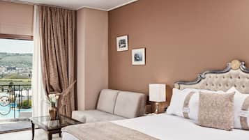 Una habitació d'hotel amb un llit, un sofà, una taula de vidre, una làmpada i dues fotografies emmarcades a la paret.