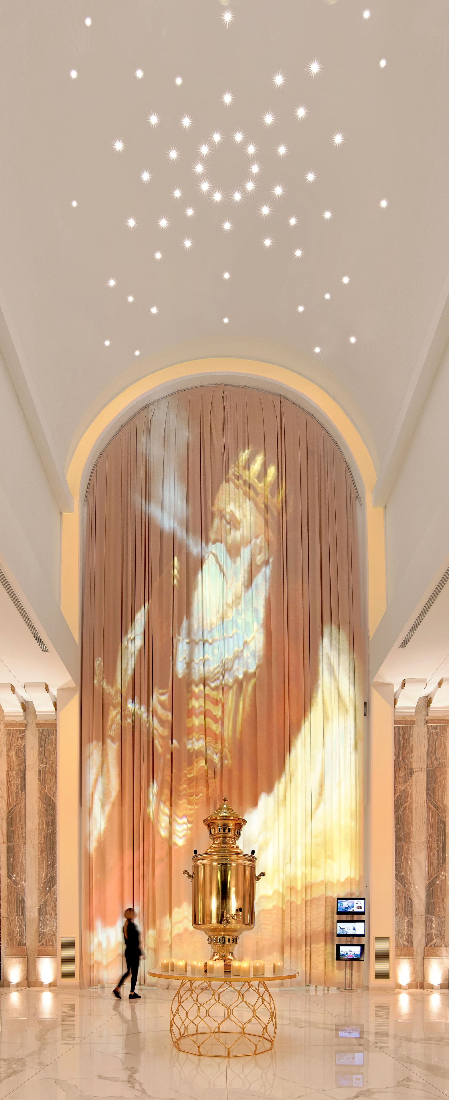 Un vestíbulo imponente con una gran pantalla de proyección, un elemento decorativo dorado y paredes de mármol.