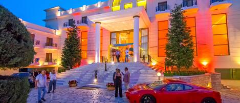 A grand hotel entrance with a modern design, featuring a large archway and a staircase leading to the main entrance.