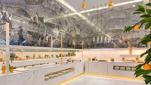 A modern hotel lobby with a marble floor, a large mural, and a reception desk with a plant display. - Epirus Palace Congress & Spa (Ioannina)