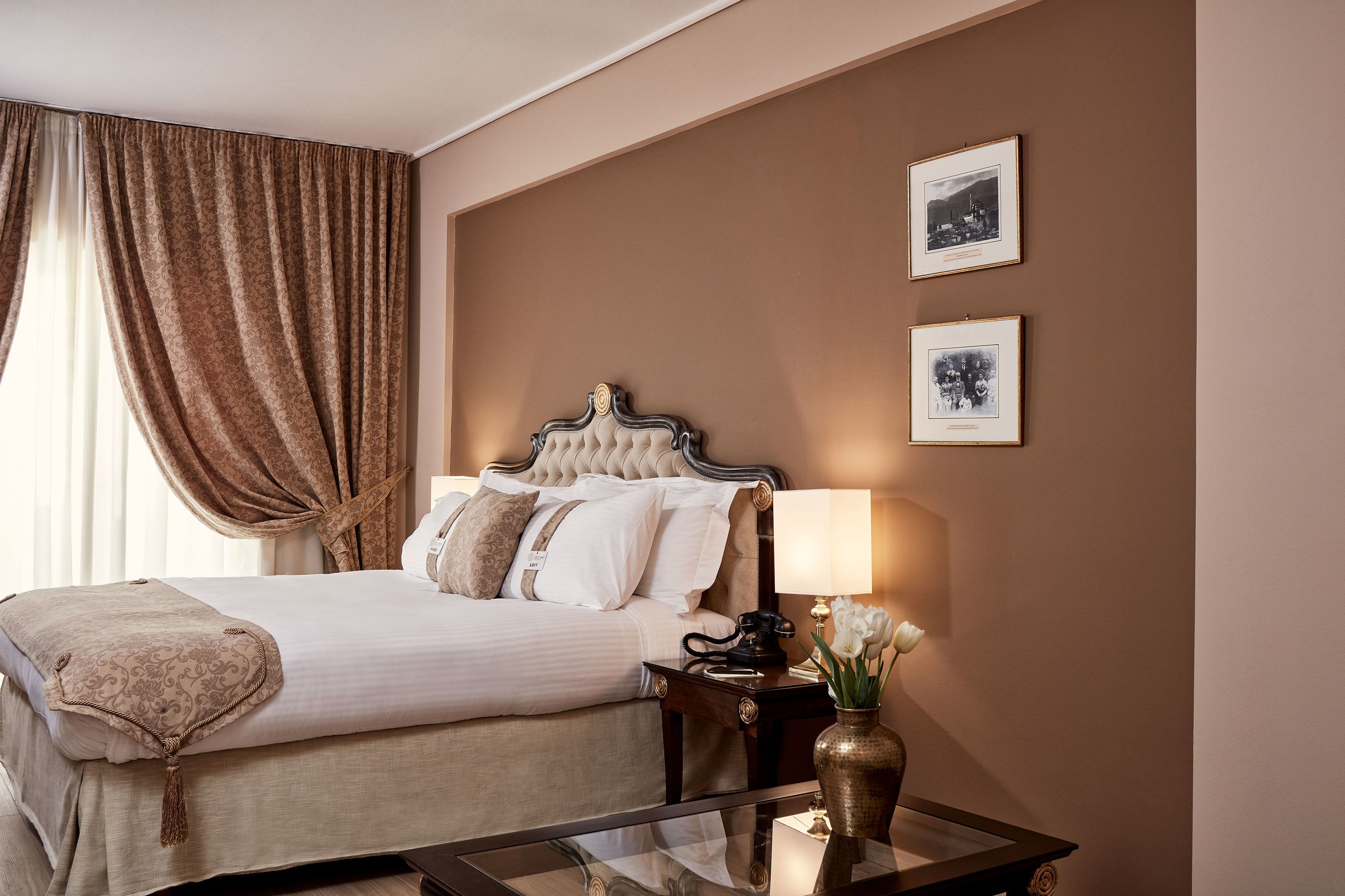 Habitación de hotel con una cama grande, una mesita de noche con una lámpara y dos cuadros en la pared.