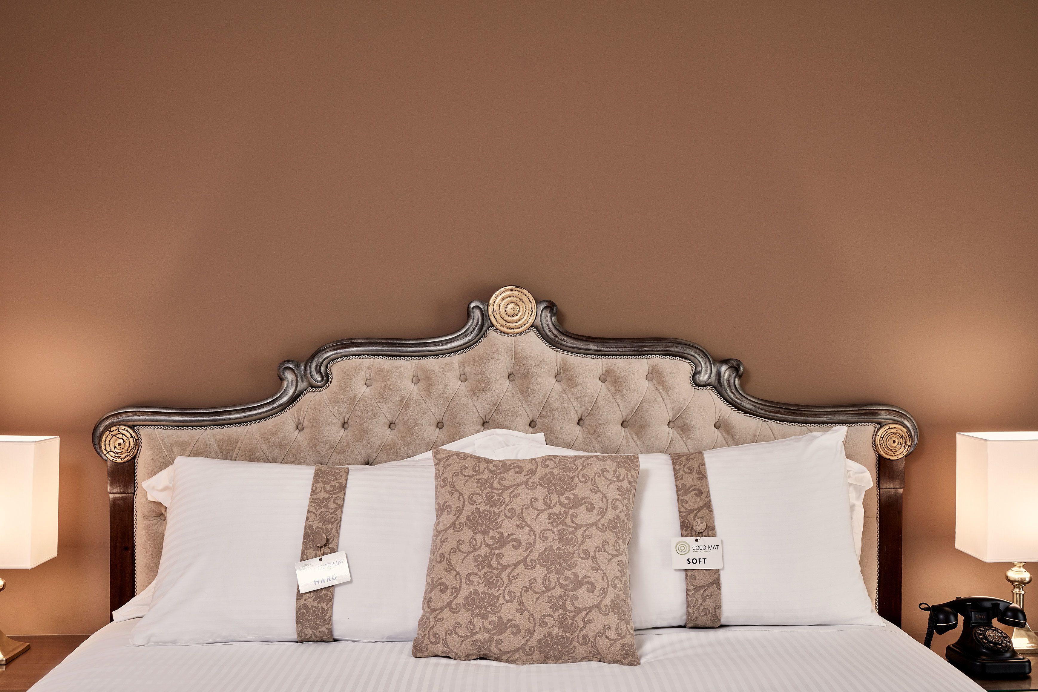A bed with a tufted headboard, white bedding, and decorative pillows.