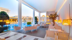 A modern hotel lobby with a pool view, comfortable seating, and ambient lighting. - Epirus Palace Congress & Spa (Ioannina)