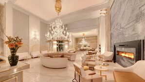 A luxurious living room with a large chandelier, a fireplace, and modern furniture. - Epirus Palace Congress & Spa (Ioannina)