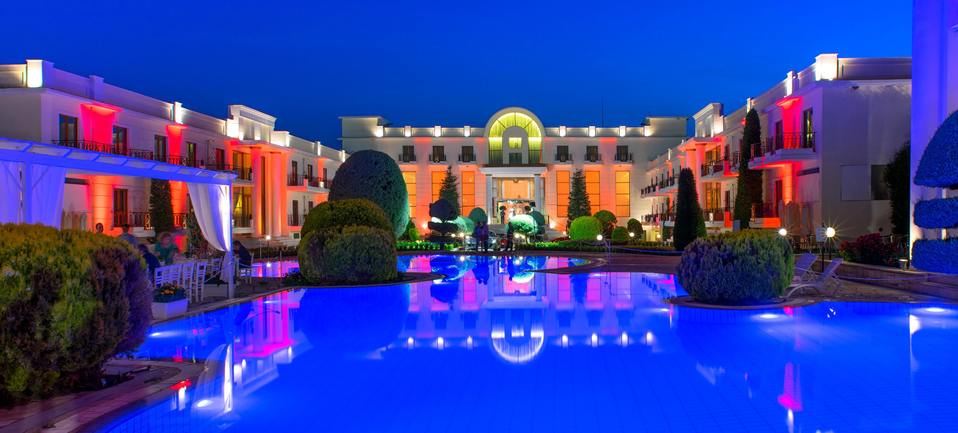 Un hotel con piscina central, varios balcones y una fachada bien iluminada.