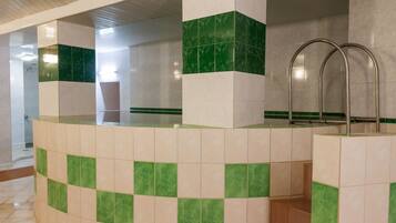 Bathroom features a checkered tile floor and walls, a bathtub, and metal handrails for support.