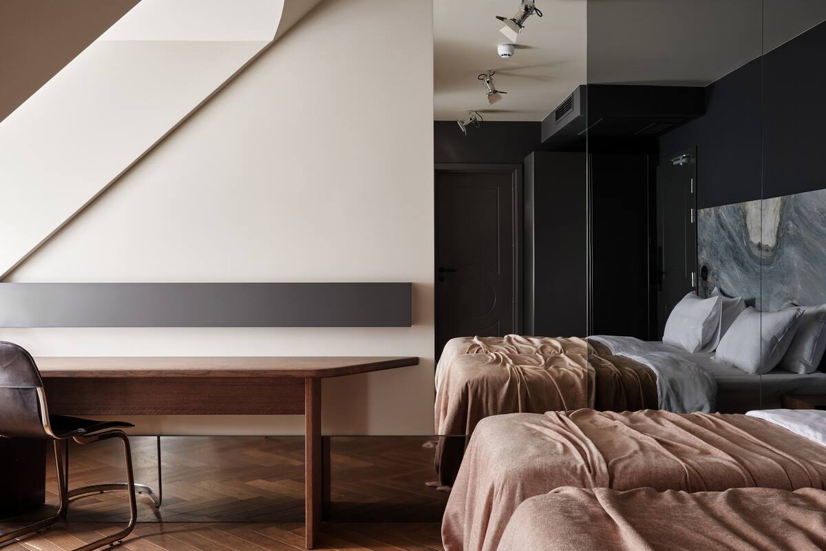Un dormitorio moderno con un escritorio de madera, una cama con cabecera y un ventanal grande.