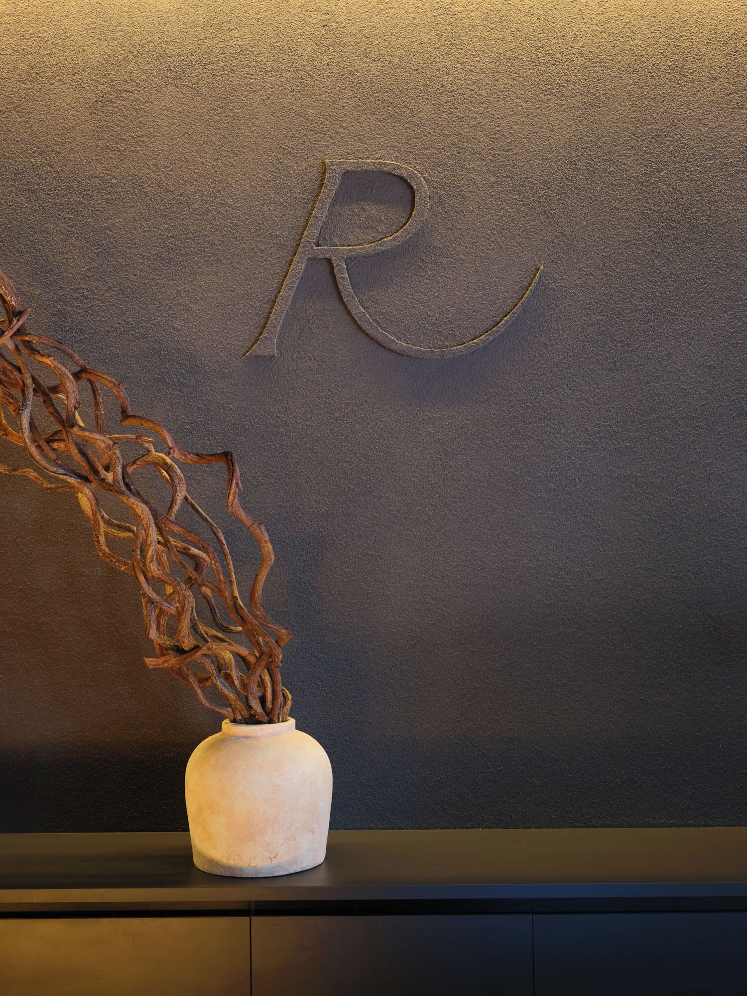 A modern interior with a textured wall and a vase with dried branches.