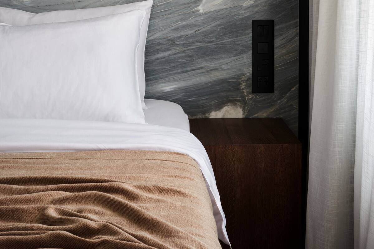 Un dormitorio con una cama, una mesita de noche y una pared decorada con un mural texturizado.