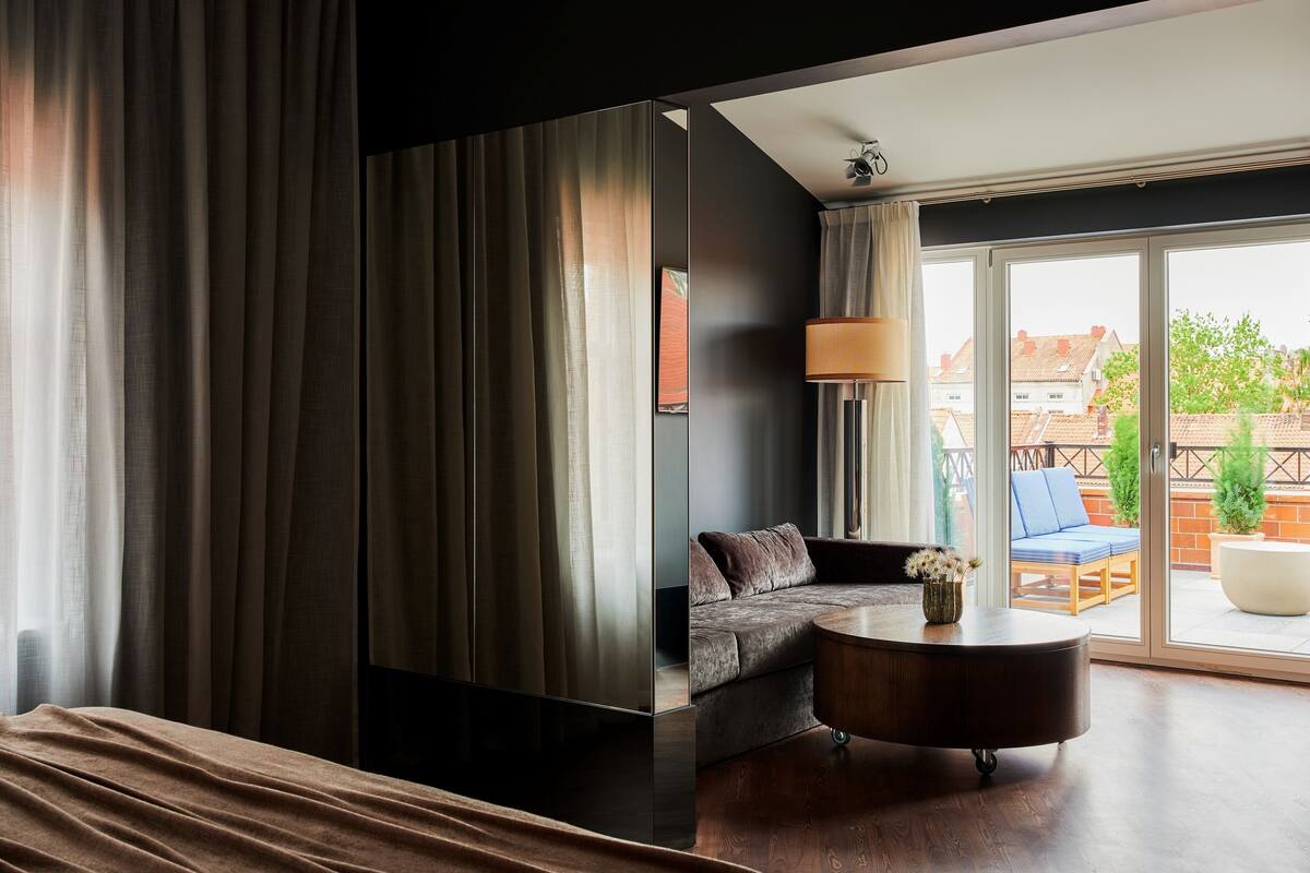 Una sala de estar moderna con un sofá, una mesa de centro y vistas al exterior a través de amplios ventanales.
