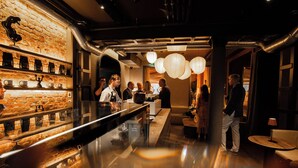 A bar area with a brick wall, shelves with items, and a polished floor. - Hotel Rėja a member of Design Hotels (Klaipeda)