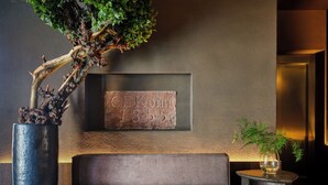 A modern lobby with a large potted tree, a cushioned seating area, and a framed plaque on the wall. - Hotel Rėja a member of Design Hotels (Klaipeda)