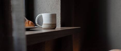 Uma caneca branca sobre um parapeito de madeira perto de uma janela.